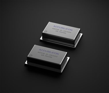 To rektangulære, metalliske elektroniske komponenter med synlige inskriptioner, placeret på en sort overflade, set fra en let fugleperspektiv.