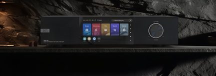 Appareil audio numérique encastré dans une paroi rocheuse, avec écran affichant des icônes colorées et un bouton rotatif
