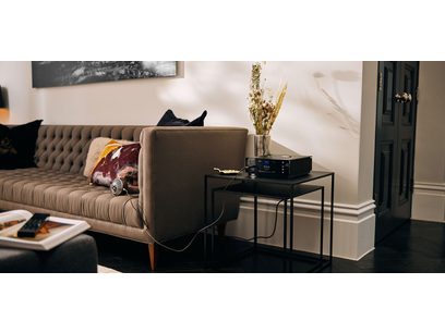 Préampli casque Naim Audio Uniti Atom Headphone Edition noir posé sur une table basse devant un canapé beige