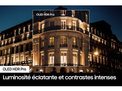 Bâtiment ancien de style haussmannien illuminé la nuit, façade ornée, balcons en fer forgé, enseigne "OLED HDR Pro"