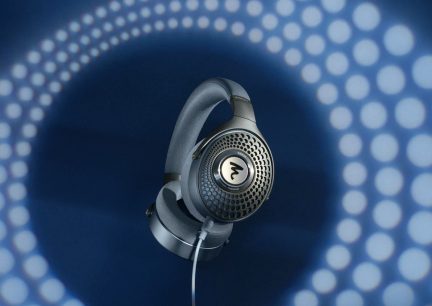Casque audio noir sur fond bleu avec motifs de points blancs, vu de profil gauche, logo blanc sur oreillette