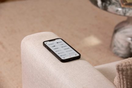 Smartphone noir posé sur une surface beige, écran allumé affichant un menu avec des options de connectivité