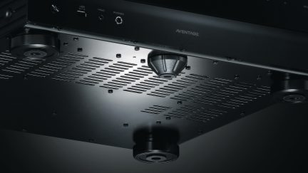 Vue en contre-plongée d'un appareil noir avec des grilles d'aération, 4 pieds circulaires et un pied central conique marqué Aventage