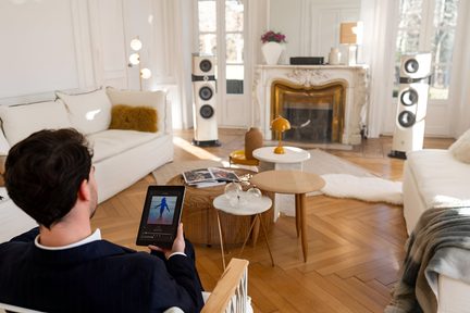 Homme assis sur un canapé dans un salon, tenant une tablette, devant une table basse avec des objets décoratifs
