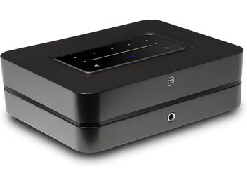 Integreret hi-fi stereo forstærker BlueSound Powernode 2025 (N331) i mat sort aluminium, rektangulært kabinet med afrundede hjørner set fra højre forperspektiv, indbygget sort blankt touchpanel på toppen med hvide ikoner og oplyst blå cirkel, frontlogo og 3,5 mm hovedtelefonudgang