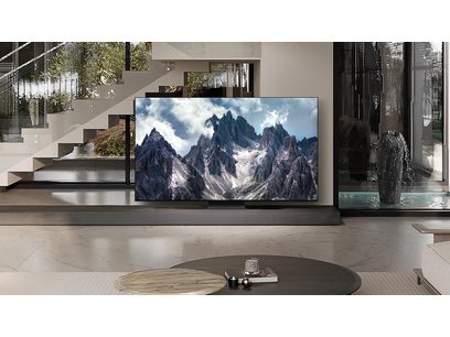 Téléviseur Samsung TQ65S95D 2024 affichant une image de montagnes enneigées, posé sur un meuble dans un intérieur moderne