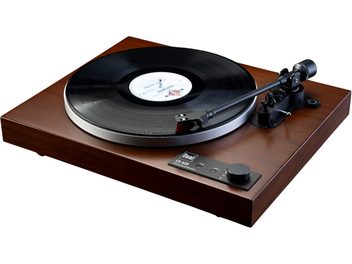 Platine vinyles hi-fi Dual CS 429 WN finition noyer, caisson rectangulaire en bois brun satiné, vue de trois-quarts avant légèrement plongeante, plateau circulaire argenté surmonté d’un disque vinyle noir, bras de lecture noir et panneau de commande noir avec bouton rotatif