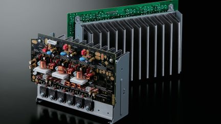 Un circuit imprimé complexe avec composants électroniques, bobines de cuivre, dissipateur thermique métallique et carte verte en arrière-plan