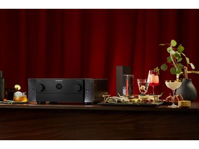 Ampli home-cinéma Marantz Cinema 50 noir, vue de face, entouré de verres à cocktail, bouteilles d'alcool et plante verte