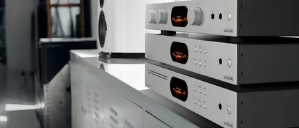 Trois appareils audio empilés en métal gris avec écrans noirs affichant des ondes orange, boutons et commandes visibles