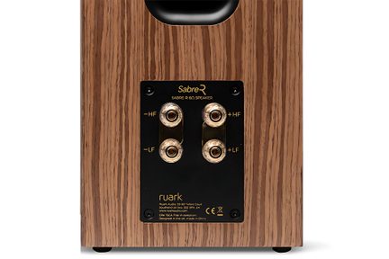 Καφέ ηχοσύστημα hi-fi με ξύλινη επένδυση, πίσω όψη που δείχνει μαύρο bass-reflex άνοιγμα και μαύρη μεταλλική πλακέτα με τέσσερις χρυσές υποδοχές σύνδεσης