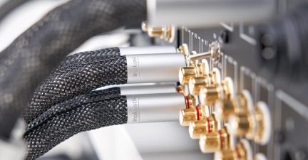 Câbles audio tressés noirs avec connecteurs métalliques argentés reliés à des bornes plaquées or sur un panneau électronique