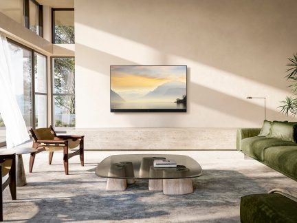 Salon moderne avec canapé vert, table basse en verre, 2 fauteuils en bois, grande fenêtre, télévision murale, lampe, plante