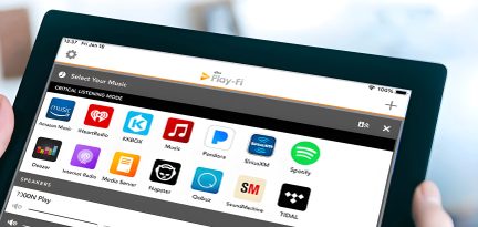 Une tablette noire affiche une interface avec des icônes d'applications musicales colorées et des options de lecture en haut.