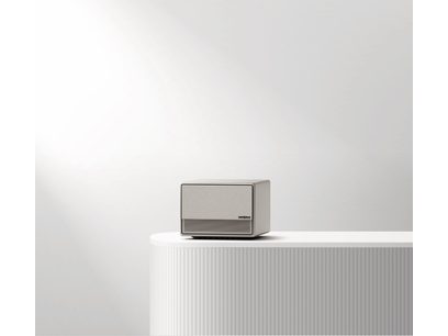 Vidéoprojecteur XGIMI Horizon Ultra gris clair, vue de face, posé sur une surface blanche striée verticalement