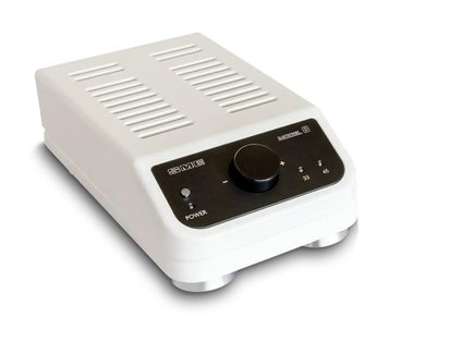 Hvidt, rektangulært elektronikhus i metal set fra trekvart forfra til højre, med sort frontpanel udstyret med en stor central cirkulær knap, en lille trykknap, to indikatorlamper og ventilationsriller på toppen