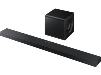 Czarny soundbar Samsung HW‑QS710F 2025 z metalu i plastiku, widok z trzech czwartych, wydłużona obudowa z rowkowaną maskownicą i centralnym panelem sterowania, w zestawie z czarnym, sześciennym subwooferem z bocznym głośnikiem.