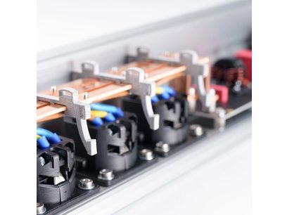 Plan apropiat interior oblic al unei multiprise Inakustik AC-3200 Filter Analog | SCHUKO, carcasă din aluminiu argintiu, bare conductoare din cupru fixate cu cleme metalice gri, prize rotunde negre și cabluri albastru-galben