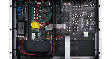 Vaade ülalt hõbedase ja musta metallkorpuse sisemusse, mis sisaldab mitmeid rohelisi ja musti elektroonikaplaate mustade ja valgete silindriliste kondensaatorite, kollase trafo, hallide lamedate lintkaablite ning punaste ja siniste toitekaablitega.