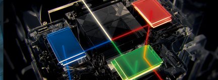 Vue de dessus d'un dispositif optique avec prismes colorés bleu, rouge, vert, noir au centre, lignes lumineuses colorées