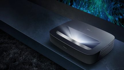 Projecteur laser noir, vue en plongée, surface supérieure lisse, grille de ventilation latérale, lumière émise vers le haut