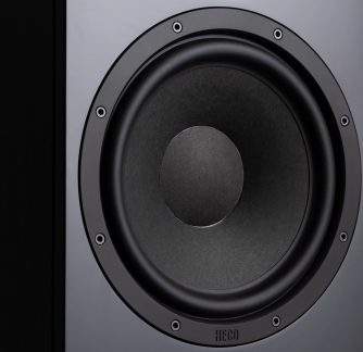 Zbliżenie na czarny, okrągły głośnik z metalową ramką i widocznymi śrubami, logo Heco widoczne na dole