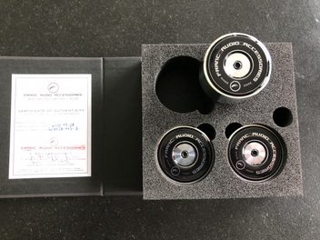 Three black circular stands and a certificate of authenticity on a textured, grainy gray background