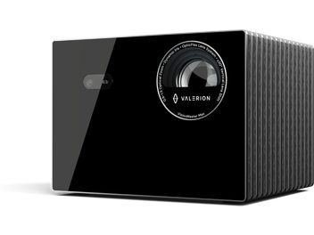 Vidéoprojecteur Valerion VisionMaster Max noir, façade en verre brillant avec large objectif circulaire entouré d’inscriptions et petit capteur rectangulaire, boîtier latéral en métal gris nervuré, vue trois-quarts avant droite