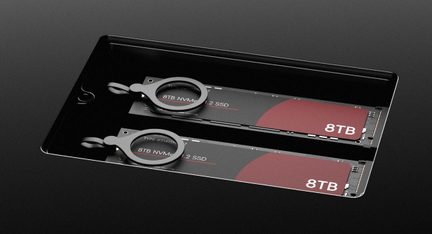 Two black NVMe M.2 8TB SSDs with red labels and metal pull rings, in a black metal drawer, oblique view