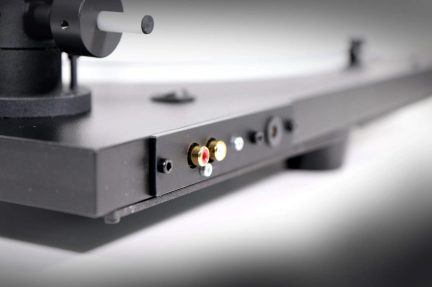Connettori audio RCA dorati su giradischi nero, vista ravvicinata laterale