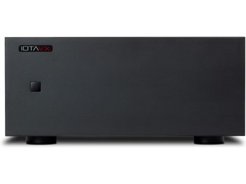 Vista frontale di un amplificatore di potenza hi-fi IOTAVX AVXP1 nero in metallo con pannello frontale opaco pieno, logo in alto a sinistra, piccolo pulsante quadrato in basso a sinistra, poggiato su due piedini cilindrici neri