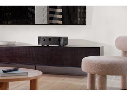 Ampli home-cinéma Marantz Cinema 50 noir, vue de face, posé sur meuble bas en bois clair, dans intérieur moderne