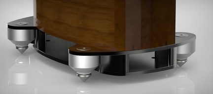 Close-up three-quarter low-angle shot of a silver metal base with conical feet and a black platform supporting a vertical brown wooden cabinet