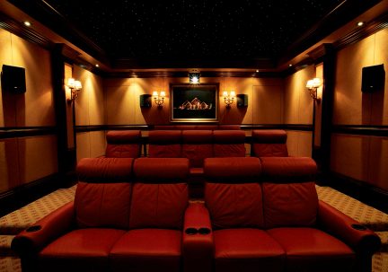 Salle de cinéma privée avec fauteuils en cuir marron, éclairage mural, écran central, plafond étoilé, vue frontale