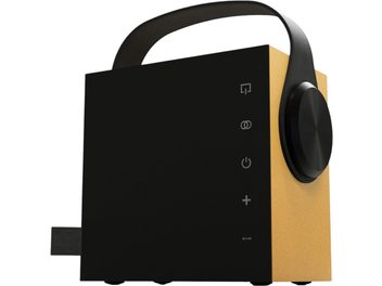 Enceinte Bluetooth portable Morel Biggie jaune, boîtier cubique bi-ton noir et jaune doré en métal mat, avec poignée arquée noire, gros bouton circulaire latéral droit et pictogrammes de commandes tactiles en façade, vue de trois-quarts avant droit