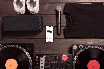 Gramofony DJ, mikrofon, głośniki, białe buty sportowe, smartfon na drewnianym stole widok z góry
