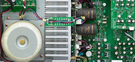 Circuit imprimé vert avec composants électroniques, haut-parleur rond argenté, dissipateurs thermiques noirs et fils colorés