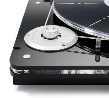 Gros plan en vue de trois-quarts avant d’une platine vinyle noire laquée avec poulie circulaire en aluminium argenté, courroie transparente tendue, plateau acrylique noir et vis métalliques apparentes