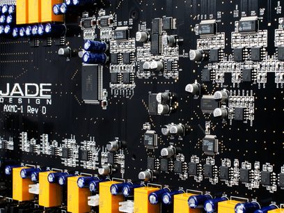 Carte électronique noire avec nombreux composants électroniques miniatures argentés et dorés, et connecteurs orange