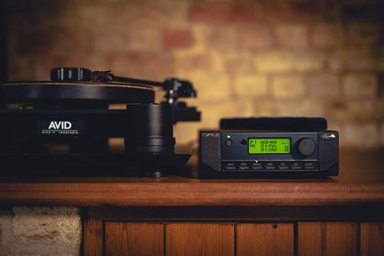 Giradischi Avid e ricevitore stereo Cyrus posizionati su una mensola in legno, visti di fronte