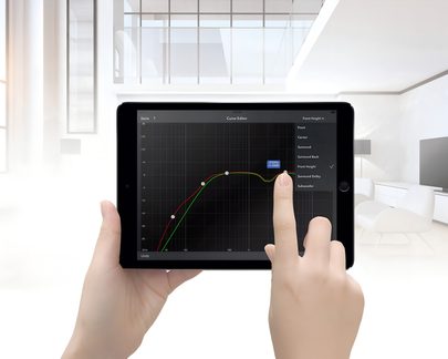Tablette noire tenue par une main gauche, écran affichant un graphique interactif, doigt droit touchant l'écran, arrière-plan lumineux