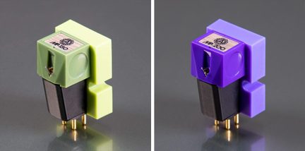 Deux cellules phono de tourne-disque, boîtiers en plastique lisse vert clair et violet avec insert supérieur en bois gravé, base trapézoïdale noire terminée par quatre broches métalliques dorées, vue en trois-quarts avant sur surface gris satiné