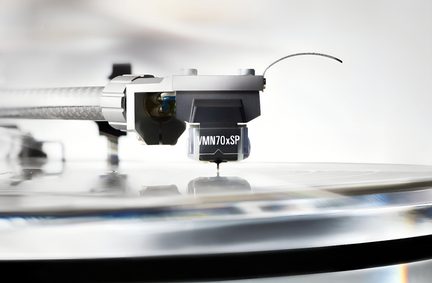 Lähivõte, külgvaade mustast plastist vinüülplaadimängija helipeast läbipaistva VMN70xSP katte ja nähtava nõelaga, mis on kinnitatud hõbedasele metallist toonarmile plaadi kohal