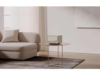 Canapé beige clair, table basse ronde en bois clair, vidéoprojecteur XGIMI Horizon Ultra gris sur la table