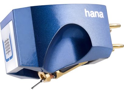 Alumīnija zilā metalizētā Hi-Fi fonogrāfa šūna Hana Umami Blue, attēlota no trīs ceturtdaļām no priekšas, kurā redzams caurspīdīgs taisnstūra korpuss, aizmugurējie zelta savienotāji un redzams lasīšanas dimants