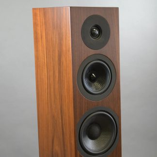 Enceinte colonne en bois avec 3 haut-parleurs circulaires noirs, vue en angle, surface lisse, arrière-plan gris uni