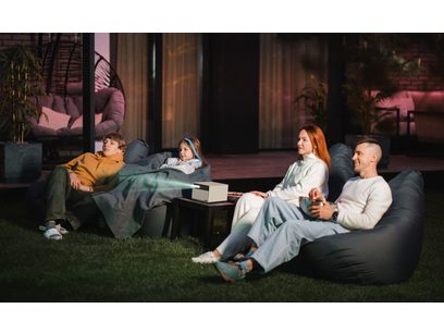 L'image montre une famille de quatre personnes assises sur un canapé dans un salon, regardant un film ou une émission sur un écran hors-champ