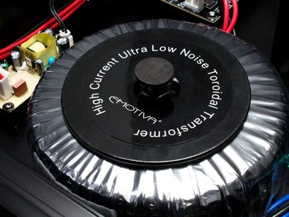 Transformateur toroïdal noir "High Current Ultra Low Noise Toroidal Transformer" dans un boîtier métallique circulaire argenté