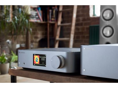Lettore audio di rete Cambridge Audio EDGE NQ color argento, vista frontale, che mostra un'interfaccia utente colorata, posizionato su uno scaffale in legno