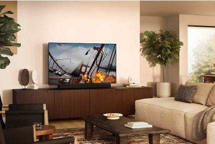 Salon moderne avec canapé beige, table basse en bois, meuble TV marron, écran plat affichant explosion, plante verte en pot